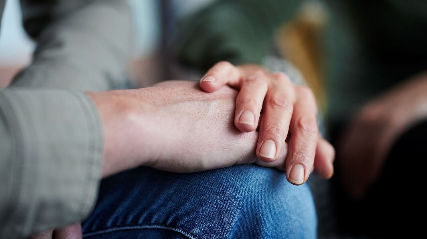 Eine Hand liegt beruhigend auf dem Unterarm einer anderen Person.